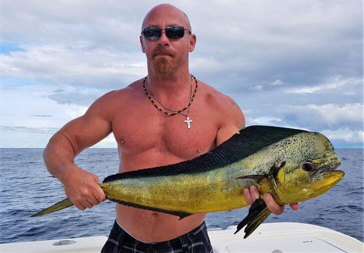 Angler with sunglasses posing with Dorado, also known as ‘Mahi-Mahi’ or ‘Dolphin’