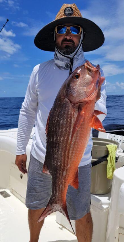 Bearded angler in big hat posing with Mullet Snapper