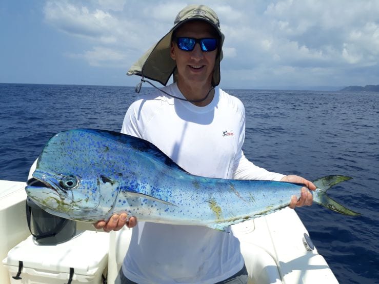 Smiling angler holding small Mahi-mahi