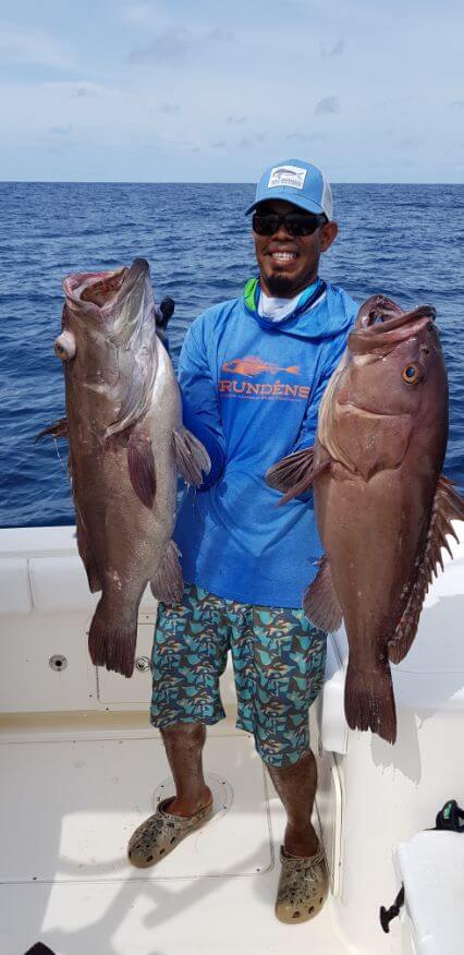 Mate holding two large snowy grouper while posing for picture