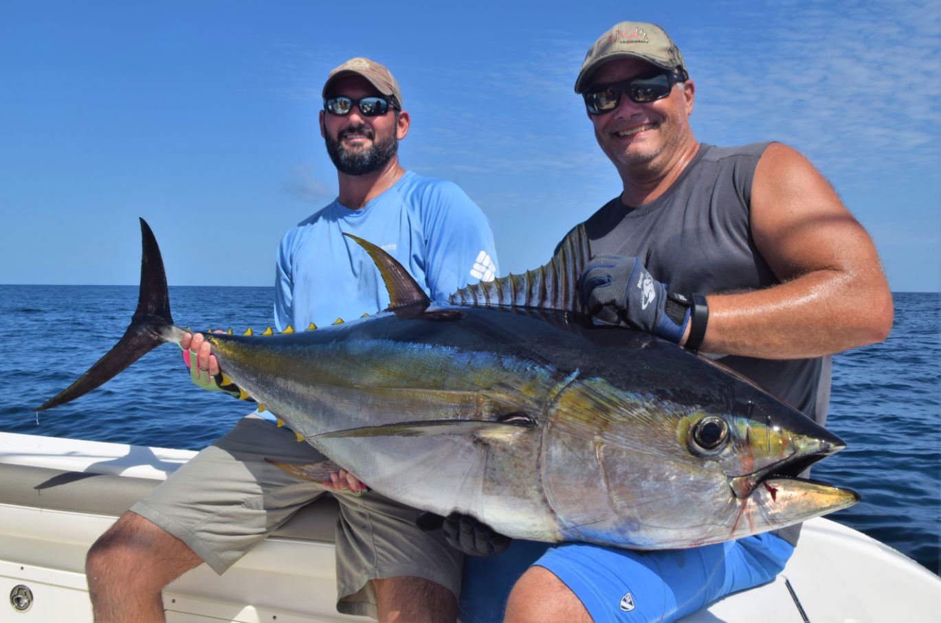 Smiling anglers posing while holding yellowfin tuna