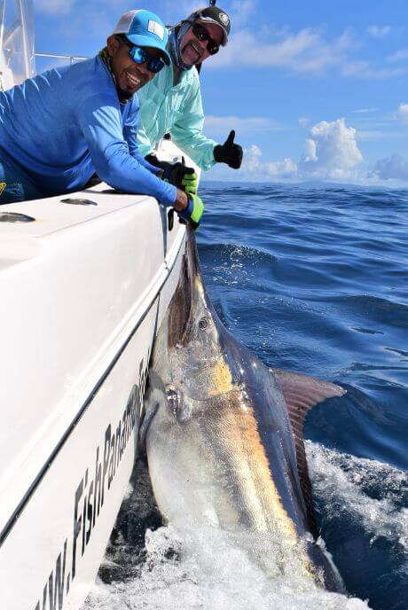 Mate releasing marlin alongside a World Cat catamaran.