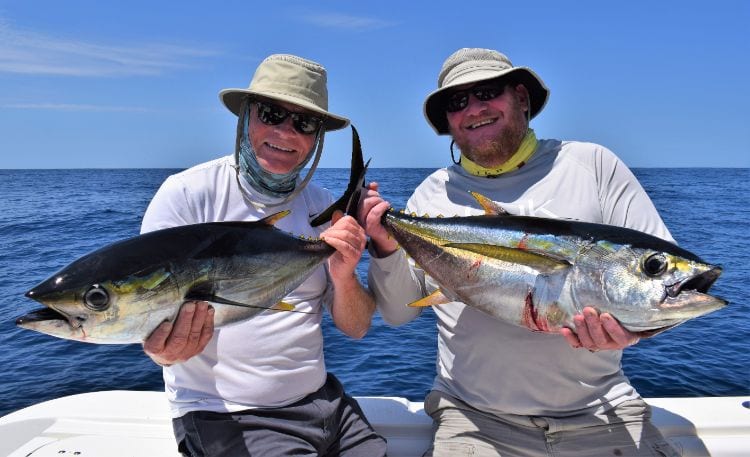 Two smiling anglers holding small yellowfin tunas