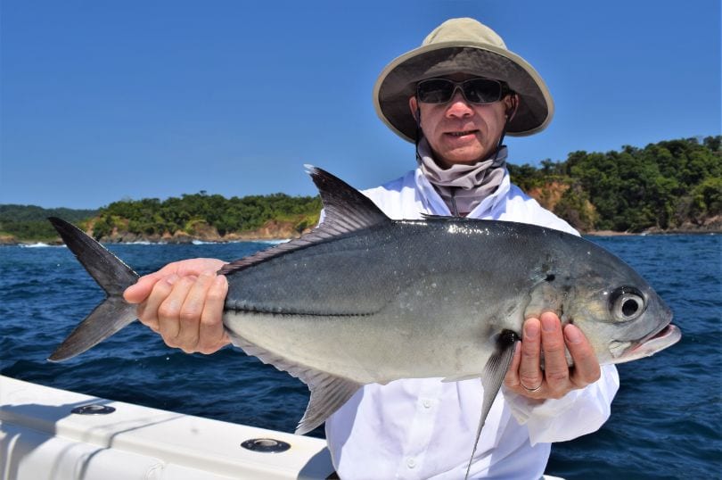 Angler holding Jack Crevalle with Isla Parida in background