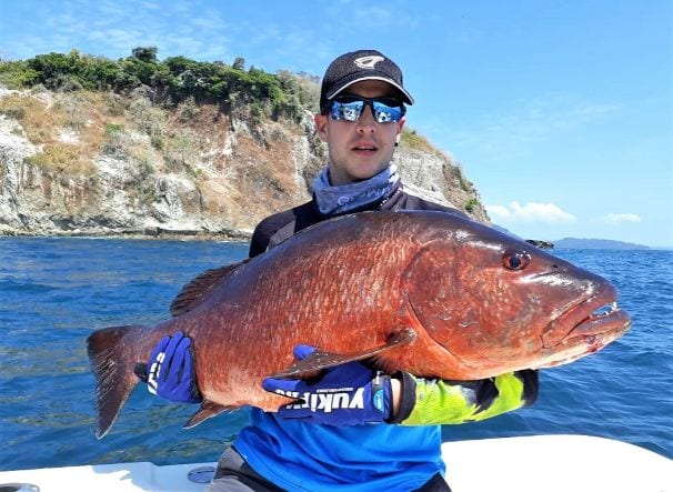Client holding cubera snapper with Isla Ladrones in the background