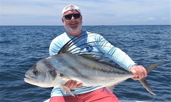 Smiling angler holding small roosterfish