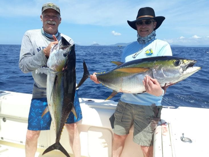 Two smiling anglers holding small yellowfin tunas