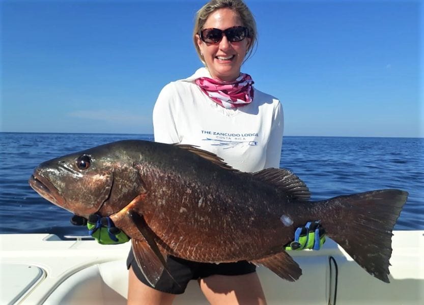 Female angler posing with very dark cubera snapper